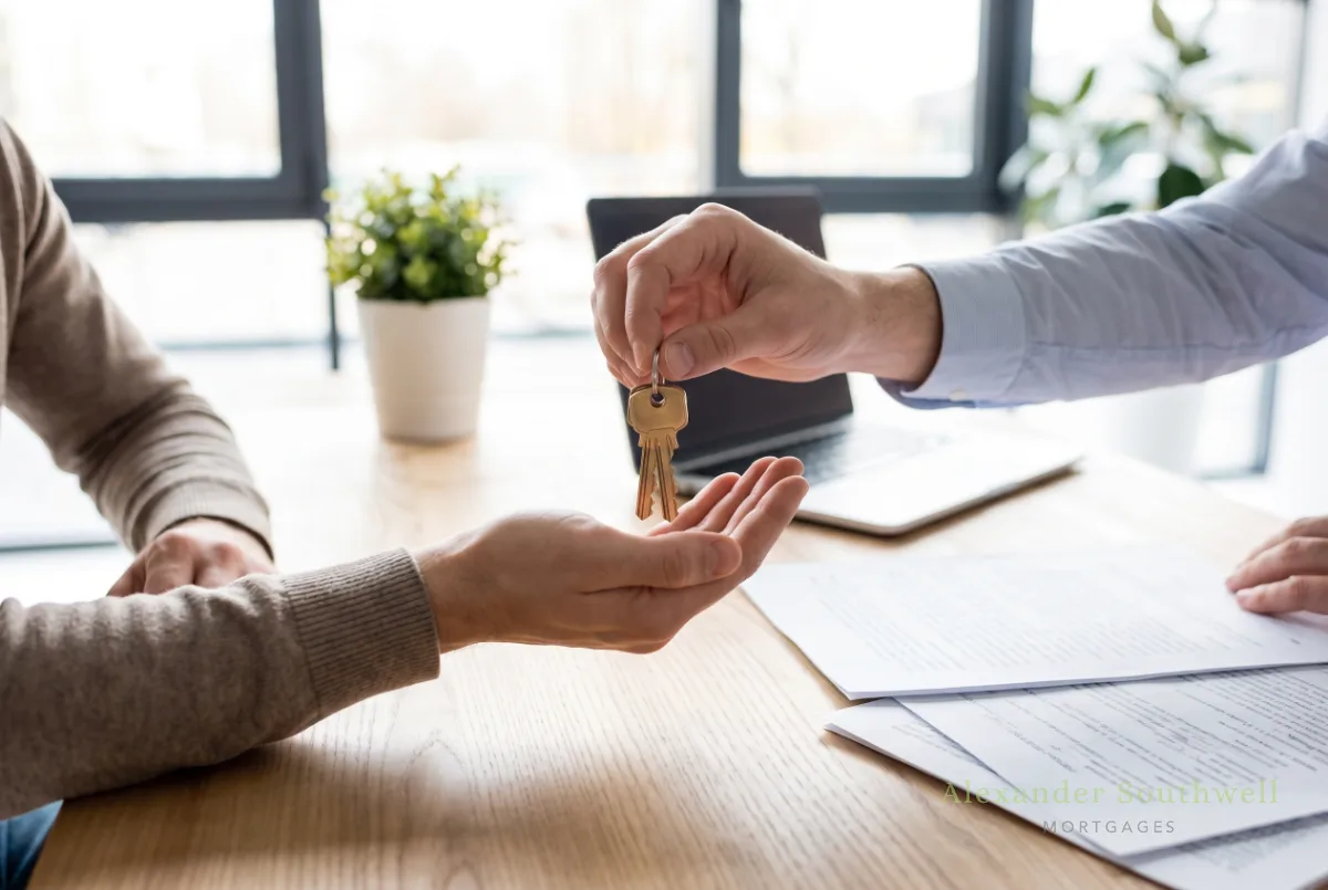 Mortgage adviser handing new house keys to a first time buyer after a 95% loan to value mortgage completes