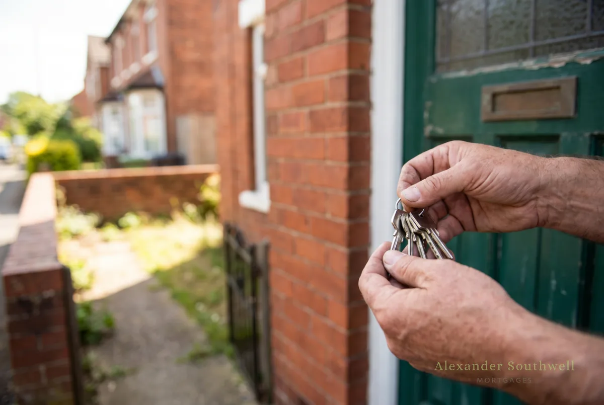 Hands holding the keys to a red brick semi detached house bought with a self employed mortgage