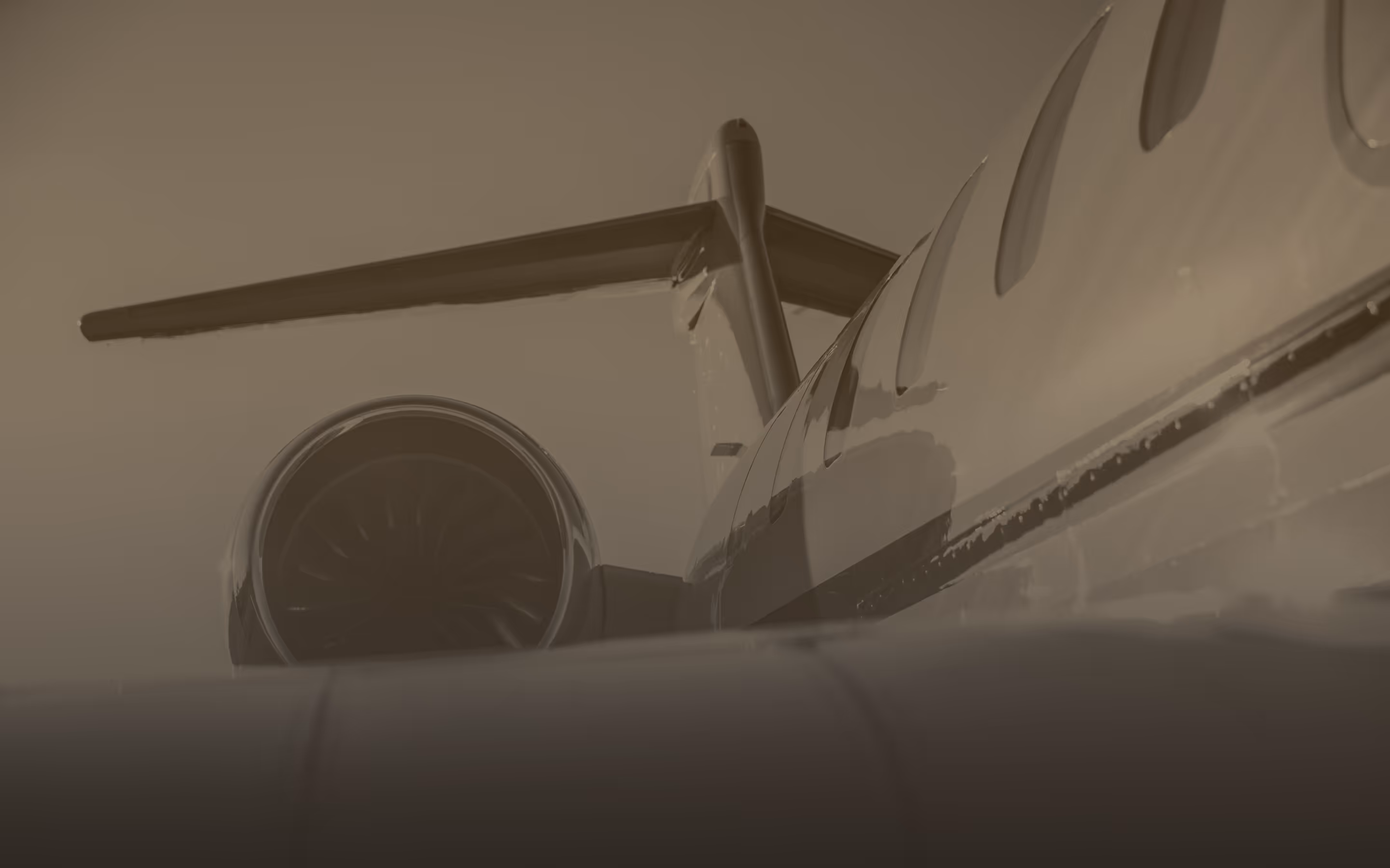 Close-up view of a private jet's rear engine and part of the fuselage with windows.