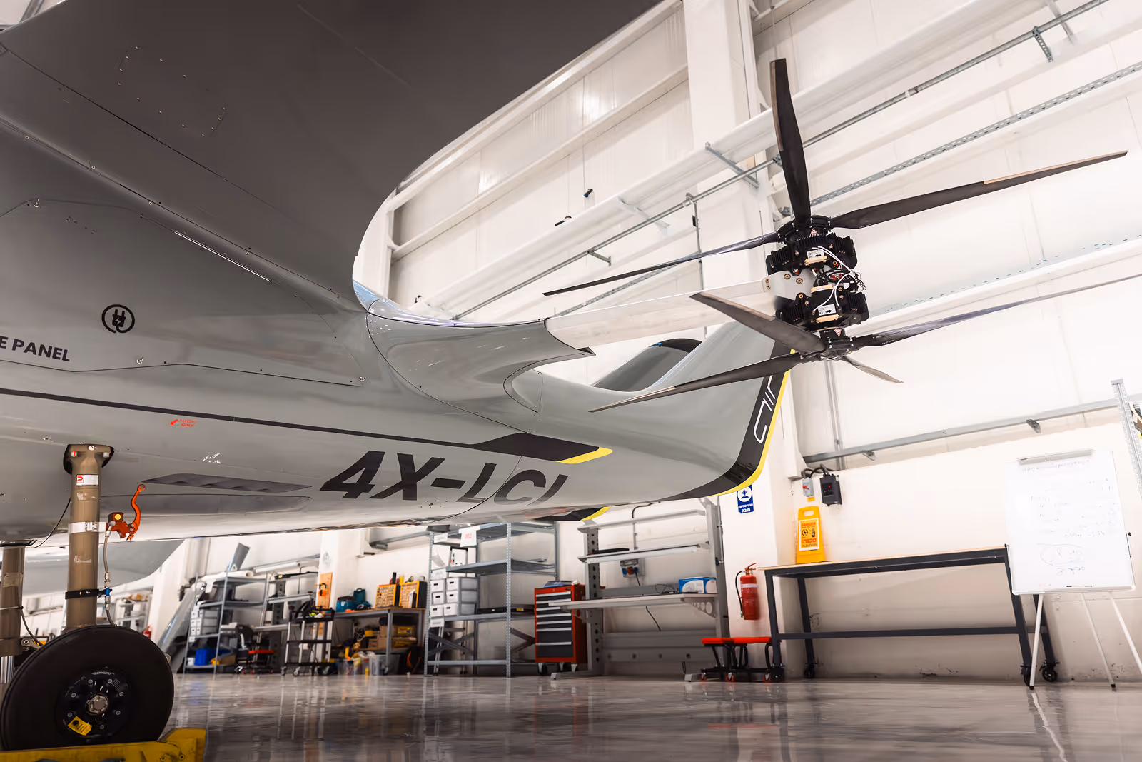 Close-up of an aircraft’s rear section with tail rotor blades in a maintenance hangar.