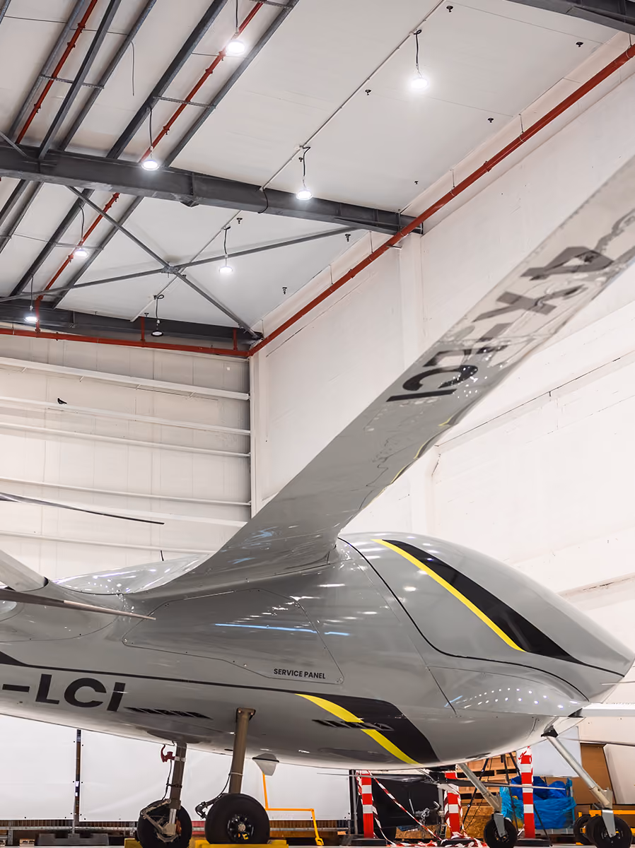 Close-up of a sleek gray aircraft tail and part of wing inside a brightly lit hangar.