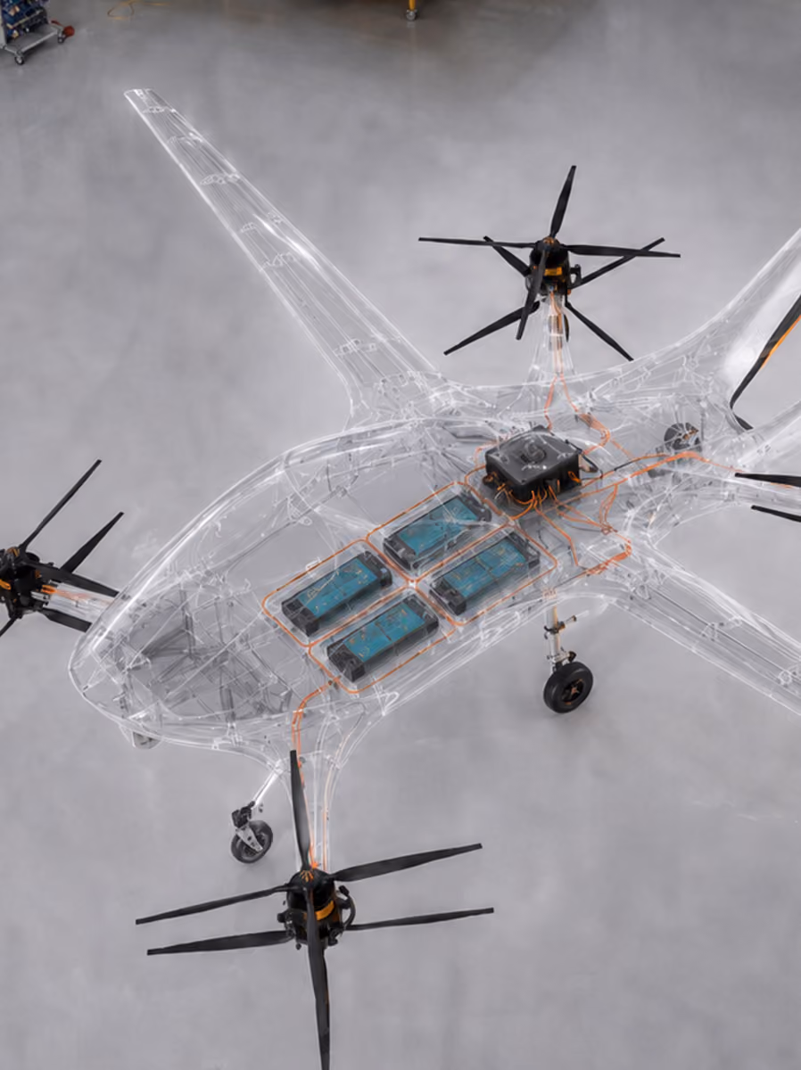 Transparent drone with visible internal battery cells and wiring on a gray floor.