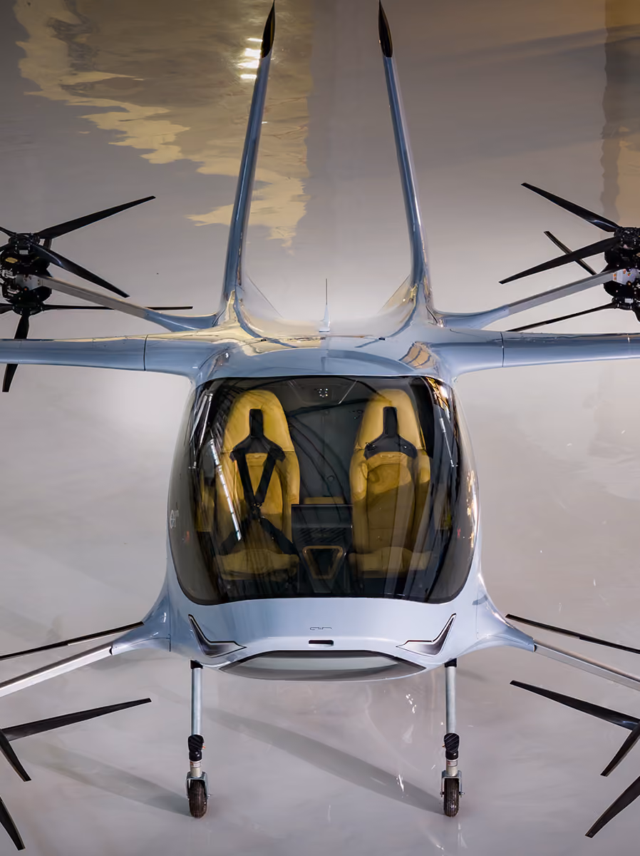 Front view of a sleek small aircraft with glass cockpit and yellow seats on a shiny surface.