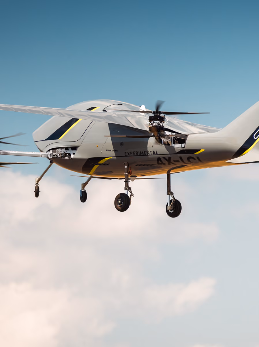 Experimental unmanned helicopter drone flying against a blue sky with clouds.