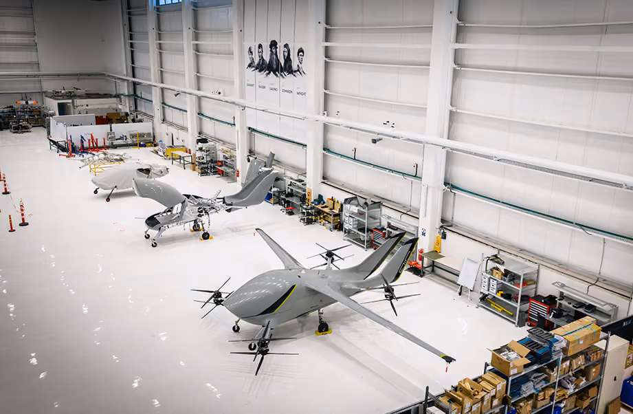 Aerial view of a clean, spacious hangar with several unmanned aerial vehicles and equipment.