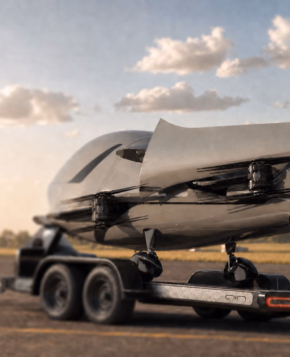 Futuristic aircraft with sleek design mounted on a trailer with dual wheels under a partly cloudy sky.