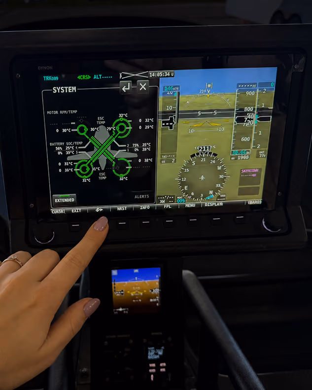 Finger pointing at touchscreen cockpit display showing system data and flight information.
