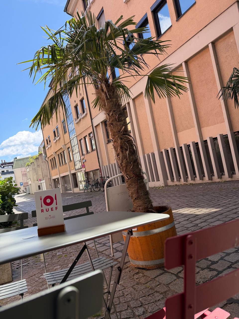Tisch mit Ruef Schild und Palme im Außenbereich