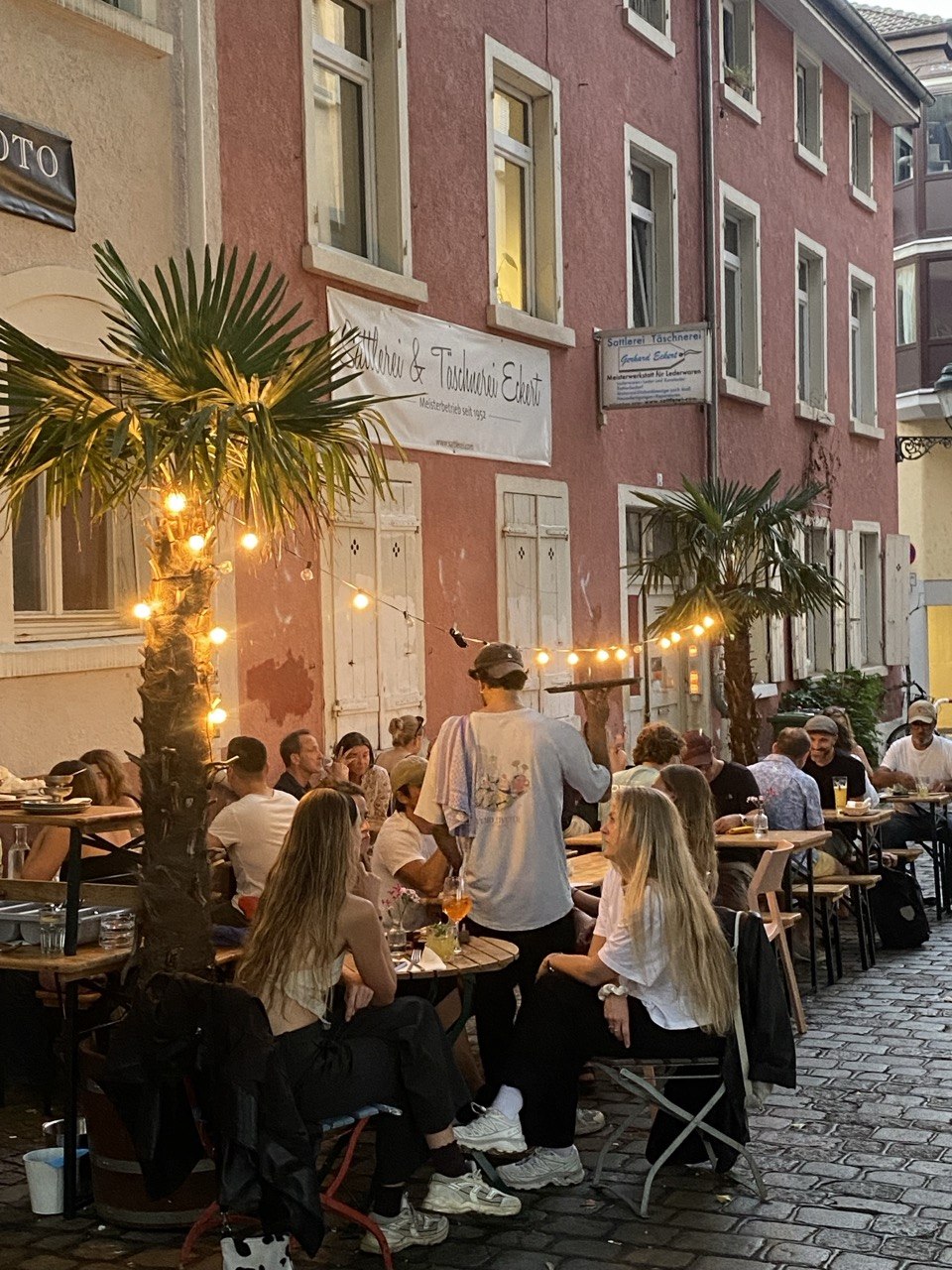 Volle Terrasse des Café Ruef am Abend mit Lichterketten