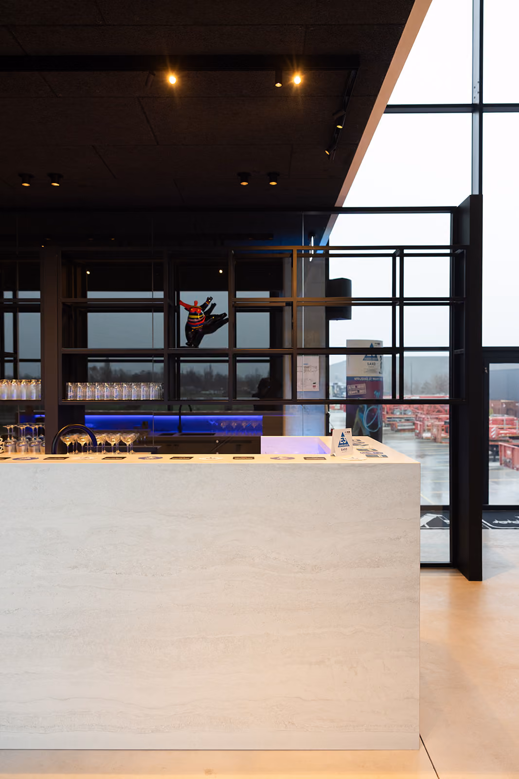 Witte marmeren bar in modern café met glazen en kleurrijk beeld aan wand.