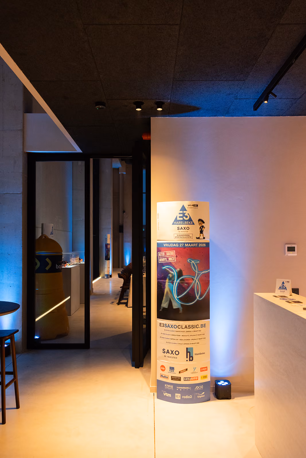 Binnenruimte met promotiebanner voor E3 Saxo Classic wielerwedstrijd op 27 maart 2026.