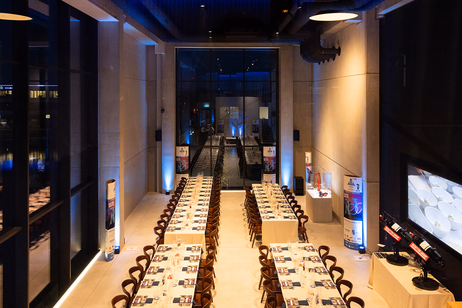 Lange tafels met stoelen in een modern zaal ingericht voor een formeel diner of evenement.
