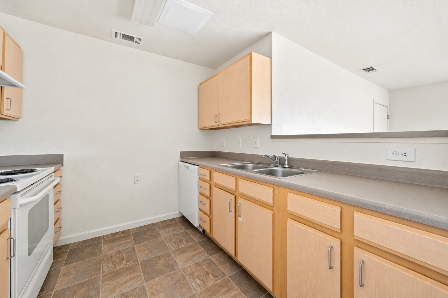 Kitchen with light wood cabinets and white appliances