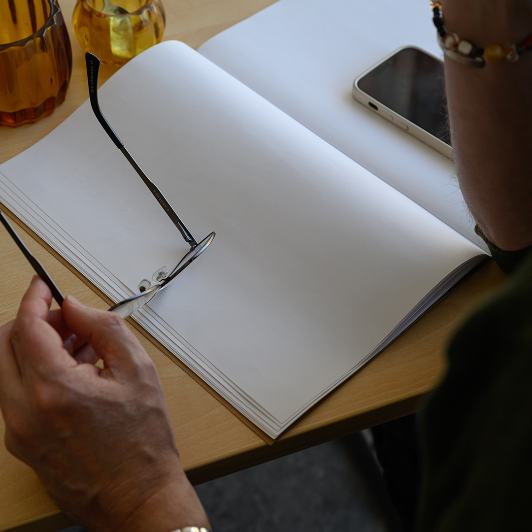 Två personer står och pratar med kaffekoppar i handen i en verkstadsmiljö – en avslappnad och genuin stund under arbetet.