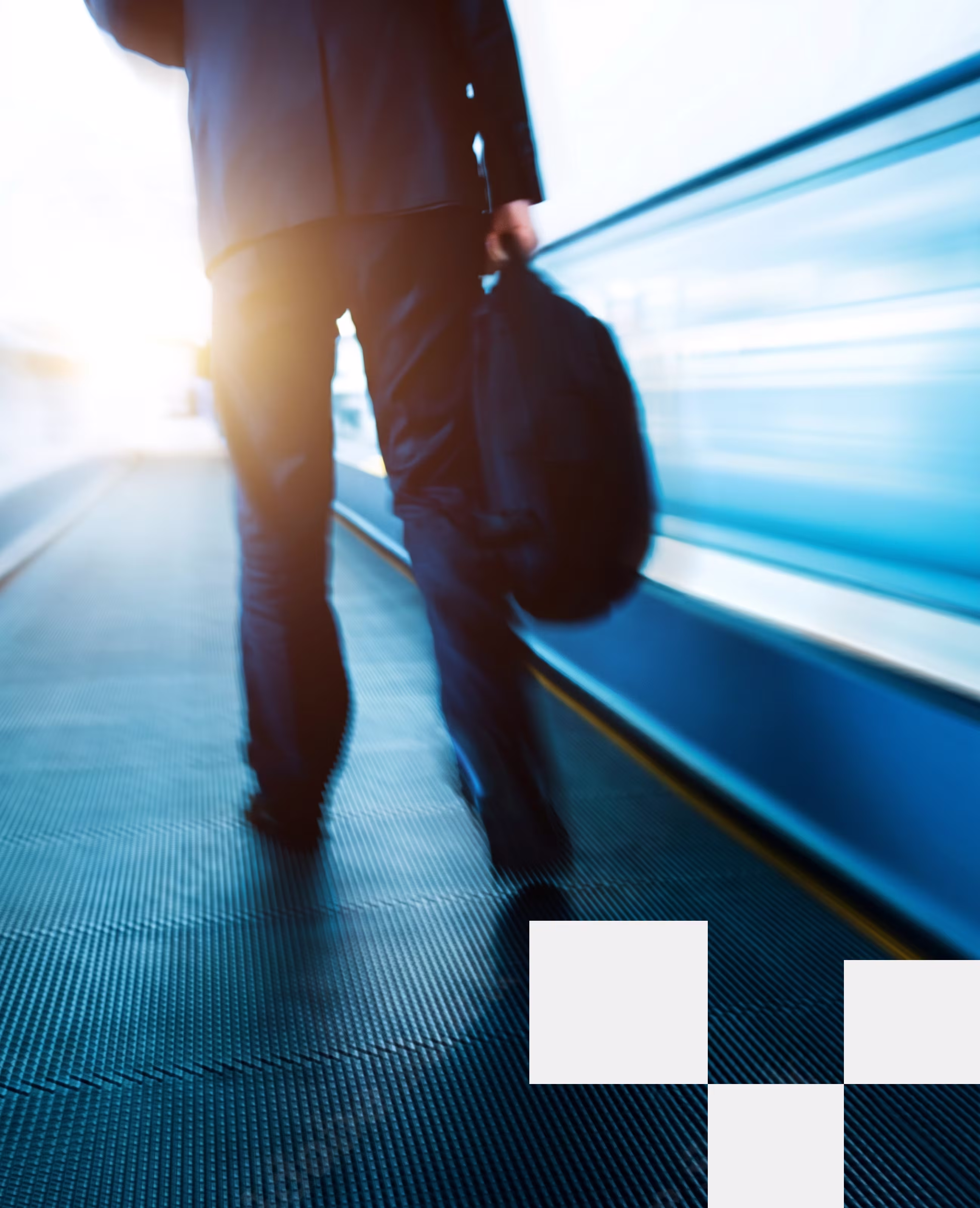Person in business attire walking on a moving walkway carrying a bag.