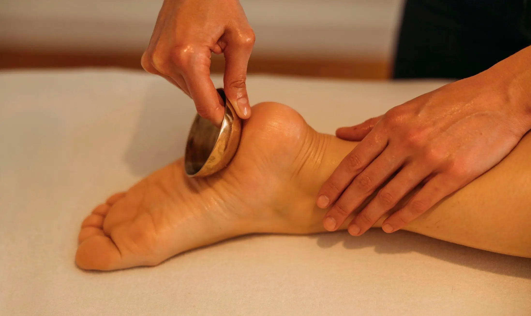 Jessy Lechipey praticienne en réflexologie plantaire périnatalité à domicile. Réflexologie plantaire avec bol chantant sur le talon.