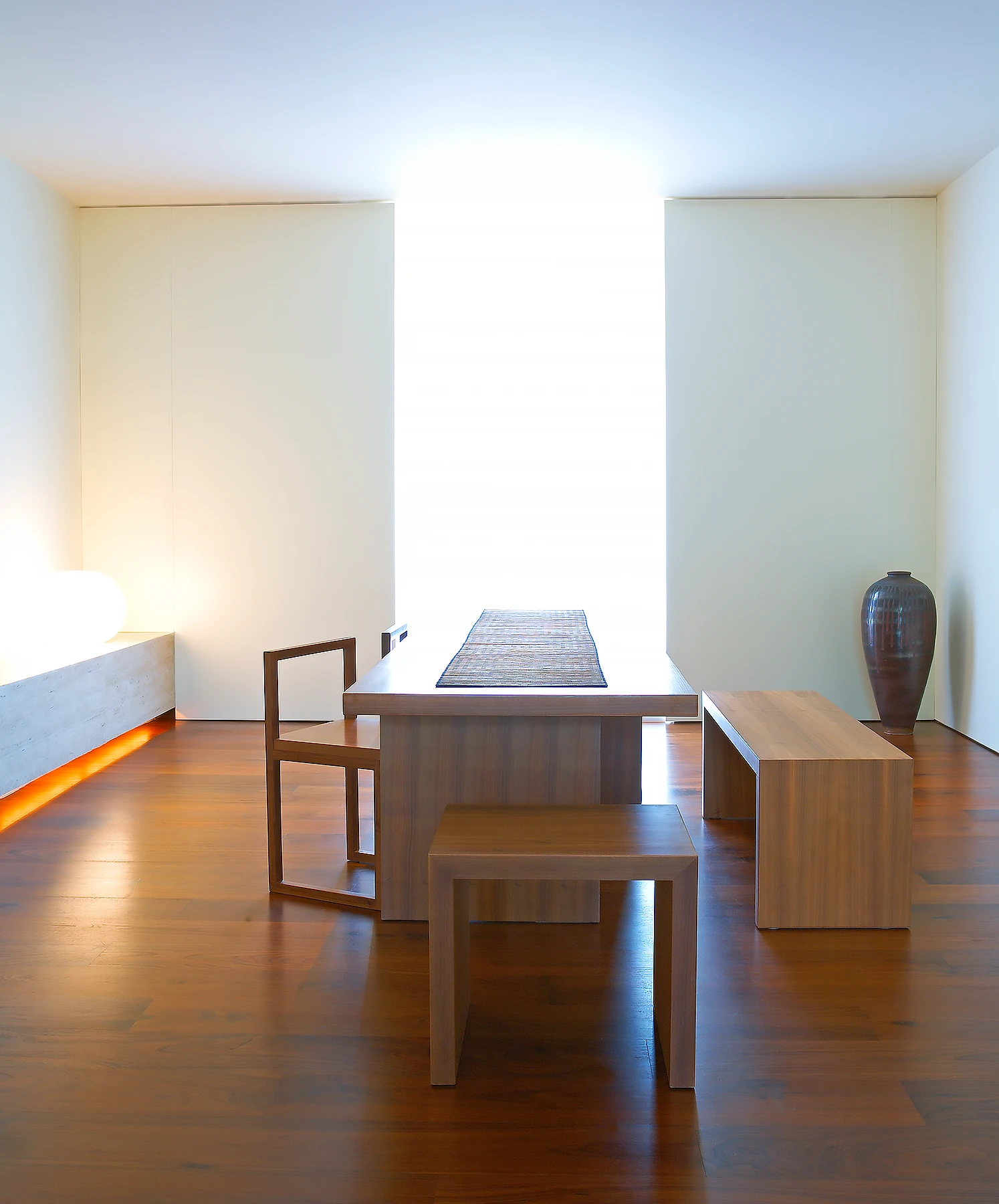 American black walnut floors are used to link the many levels and also for key pieces of fitted and bespoke loose furniture. Spaces are lit indirectly across the floor from benches, along the walls from niches and vertical slots. 