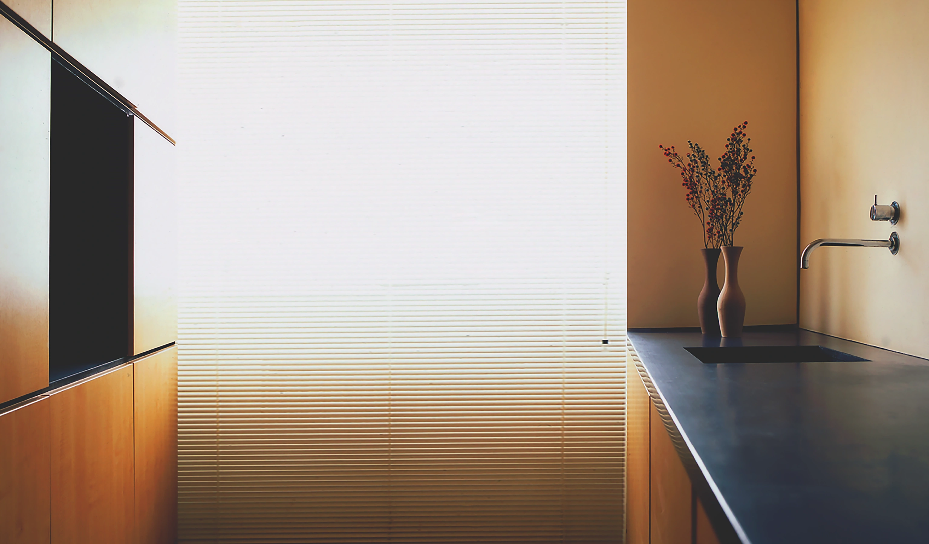 The kitchen is in oak and black granite. As the light dims, the black sink and black induction disappear.
