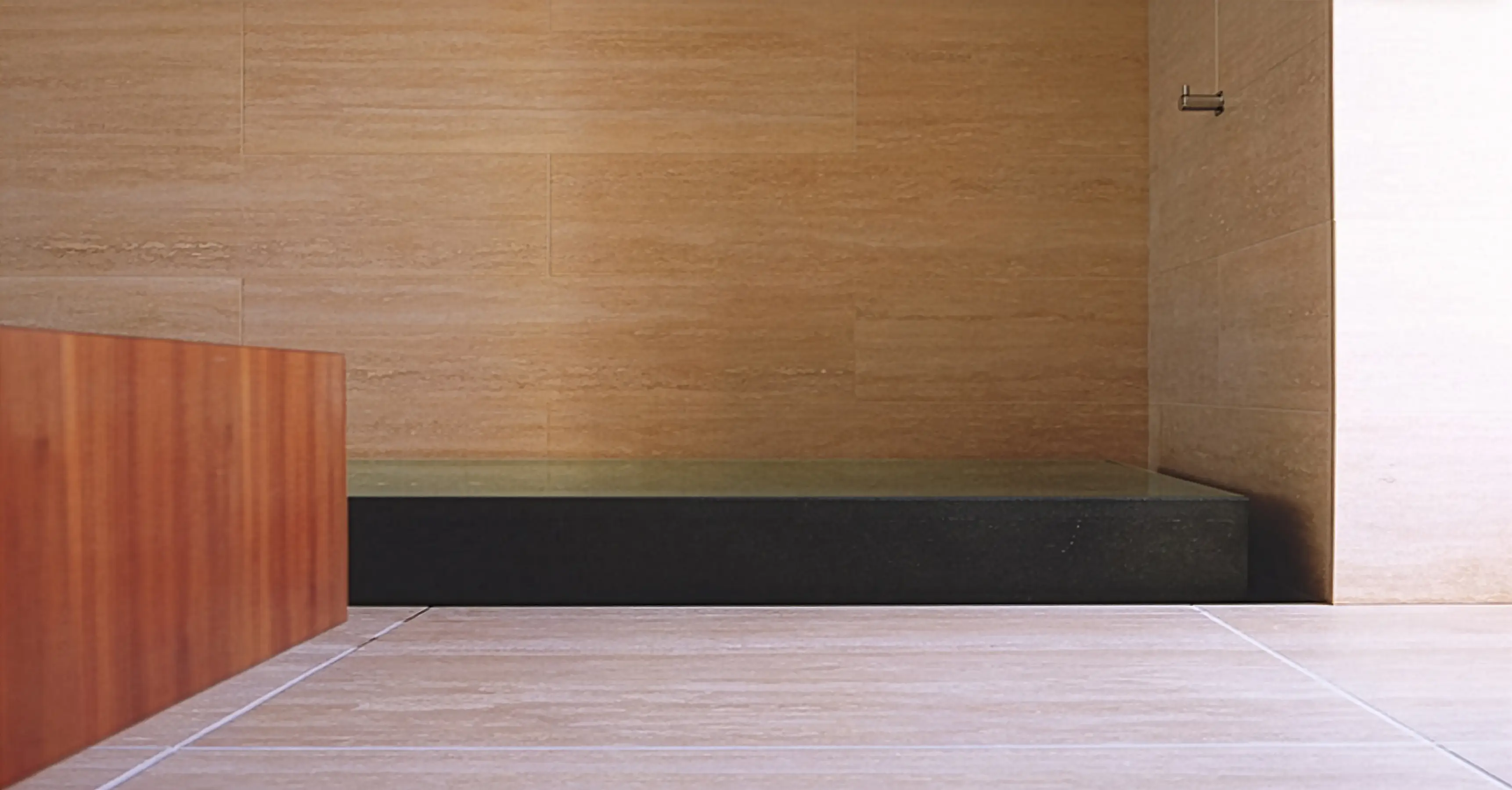 5m long sunken bath formed from black granite with an infinity edge all around. At one end, the granite is a mere shallow depression in the stone and forms the shower tray.