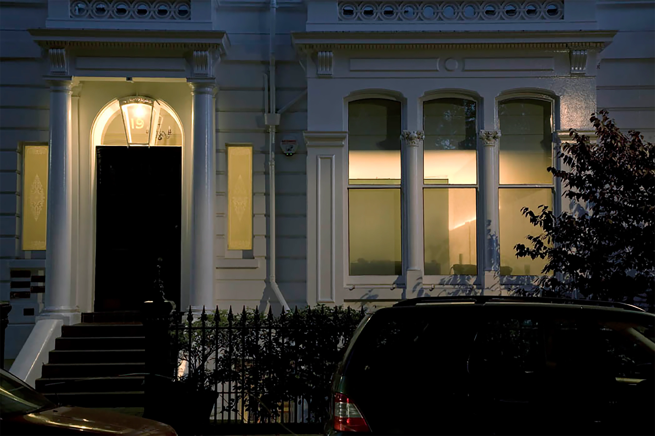 From the exterior of this pair of grand villas, a glowing glass cube in a halo of light can be glimpsed.
