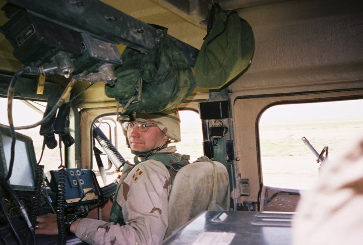Tony Cerella in military uniform inside a Humvee, showcasing his Army leadership background.