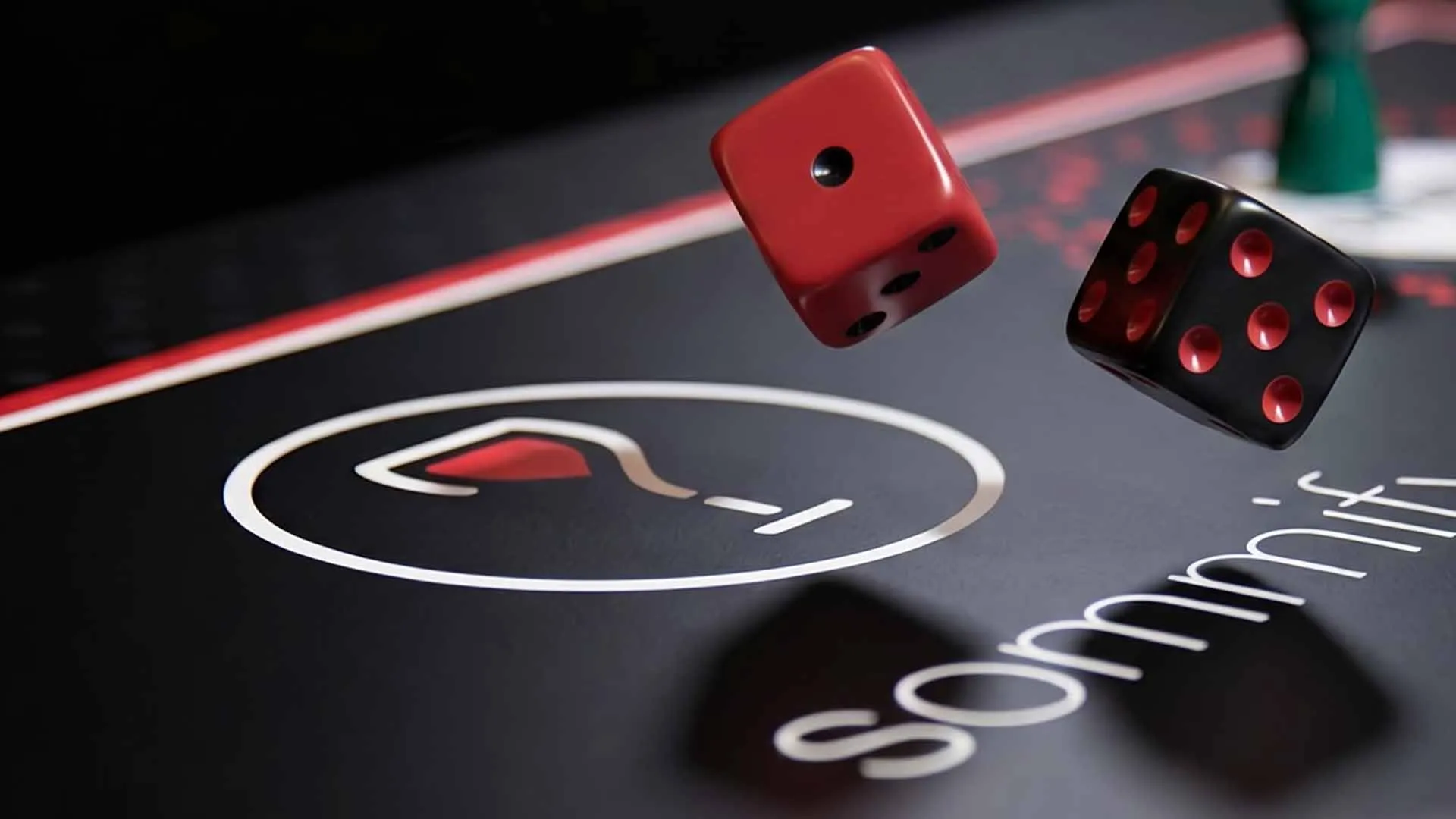 Red and black dice caught mid-air above the matte black Sommify board, the white wine glass logo ring and sommify wordmark below