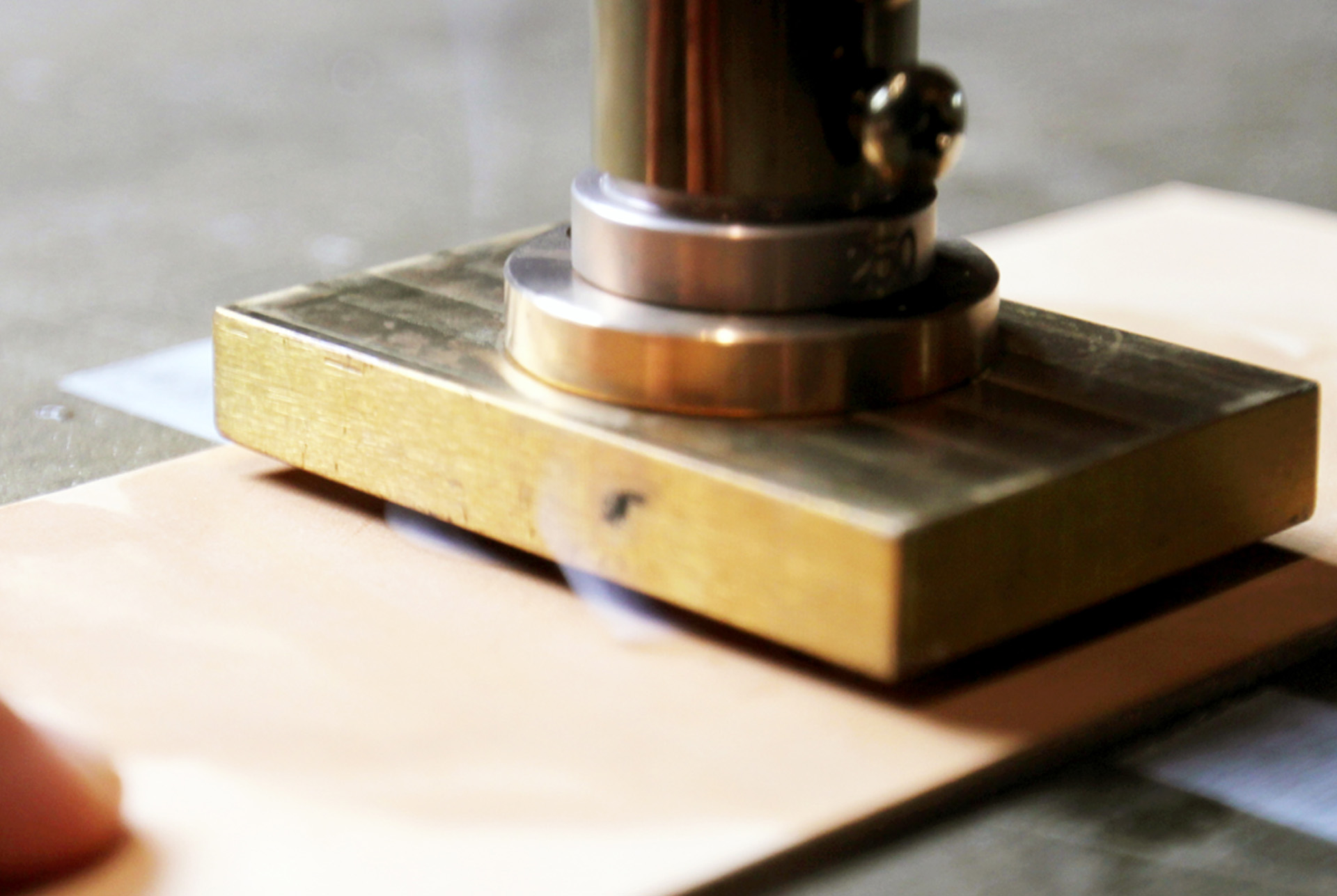 Brass embossing die pressed onto a J. James leather flask wrap