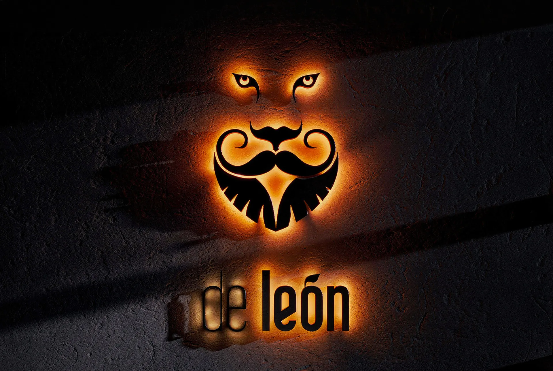 De León shopfront sign lit at night, the lion and beard mark glowing orange above the de León wordmark