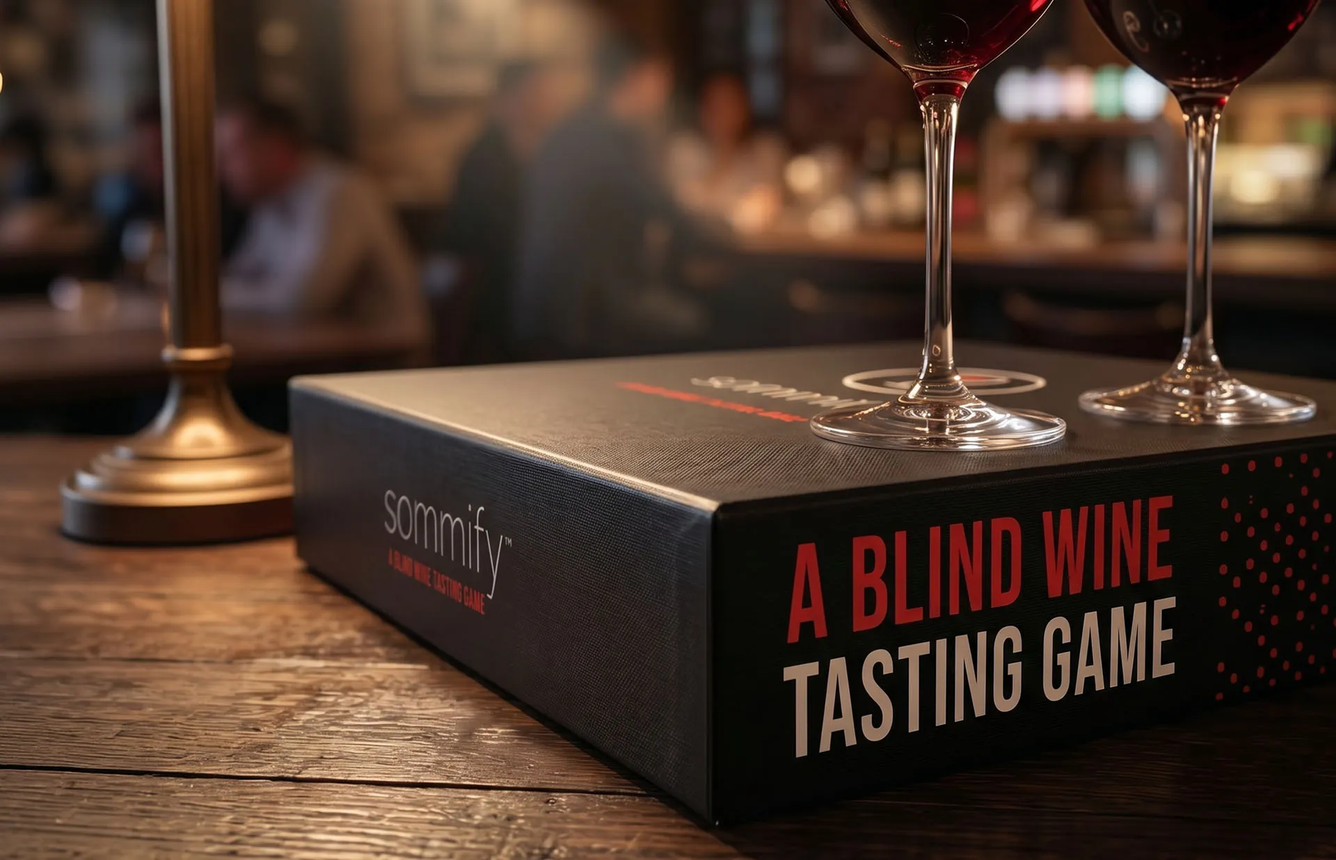 Sommify retail box on a bar reading A Blind Wine Tasting Game beside two glasses of red wine