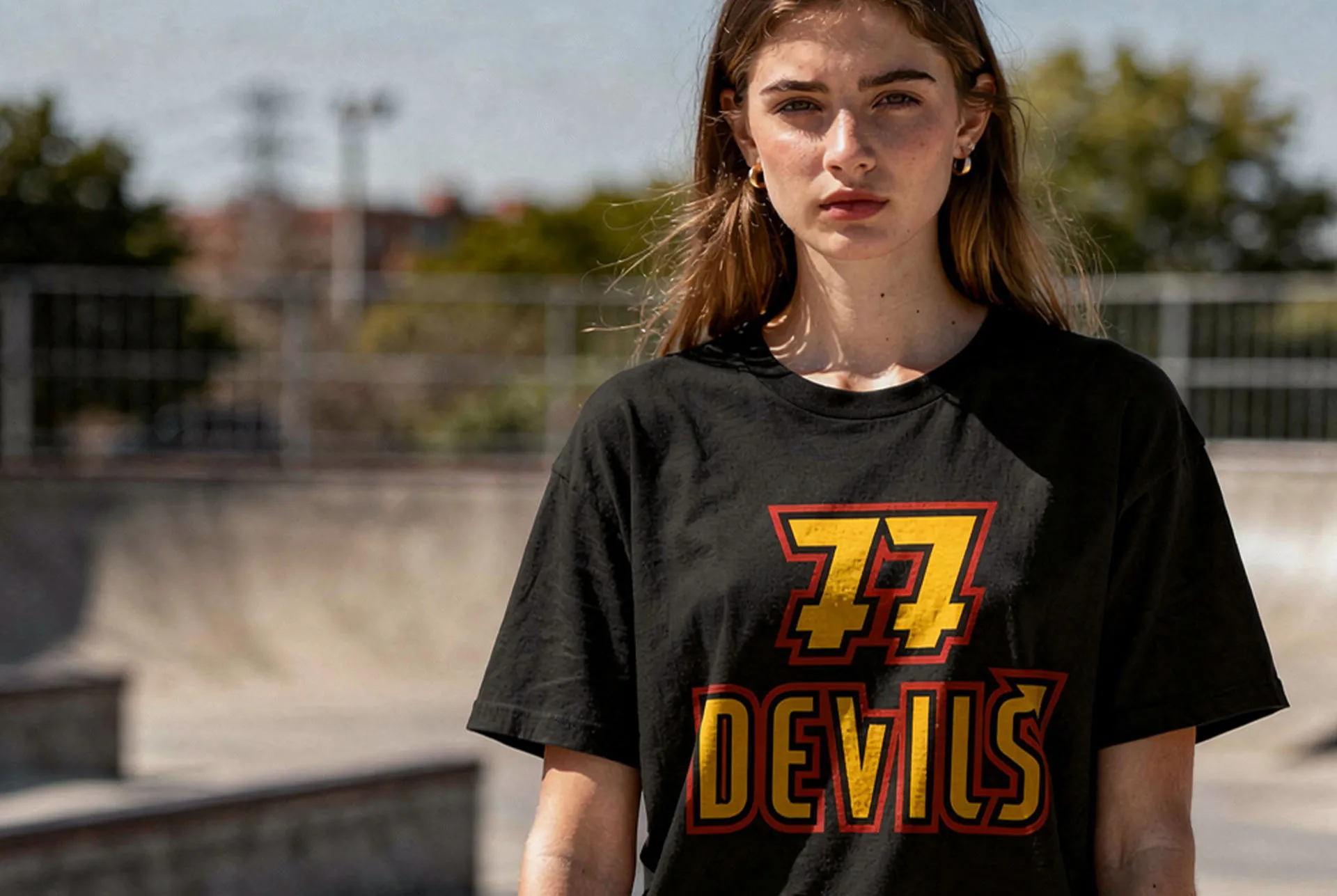 A woman at a skate park wearing a black 77 Devils tee
