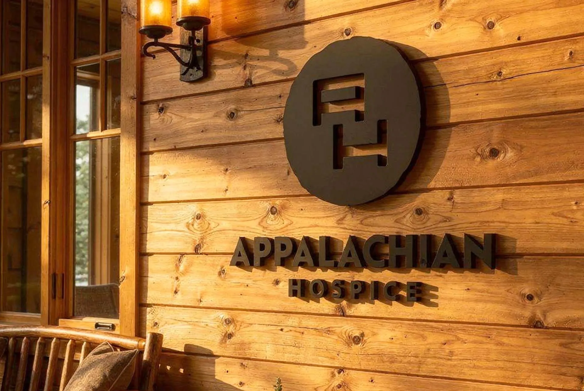The Appalachian Hospice mark as a dark disc sign on a timber wall above the name