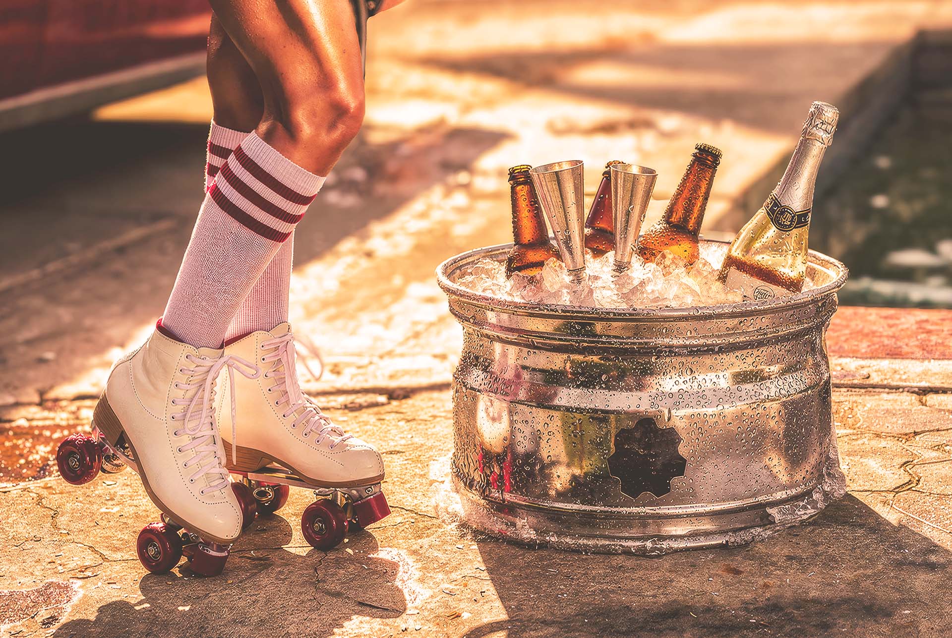 Gearbox car-rim ice bucket filled with bottles on ice beside roller skates, poolside lifestyle campaign