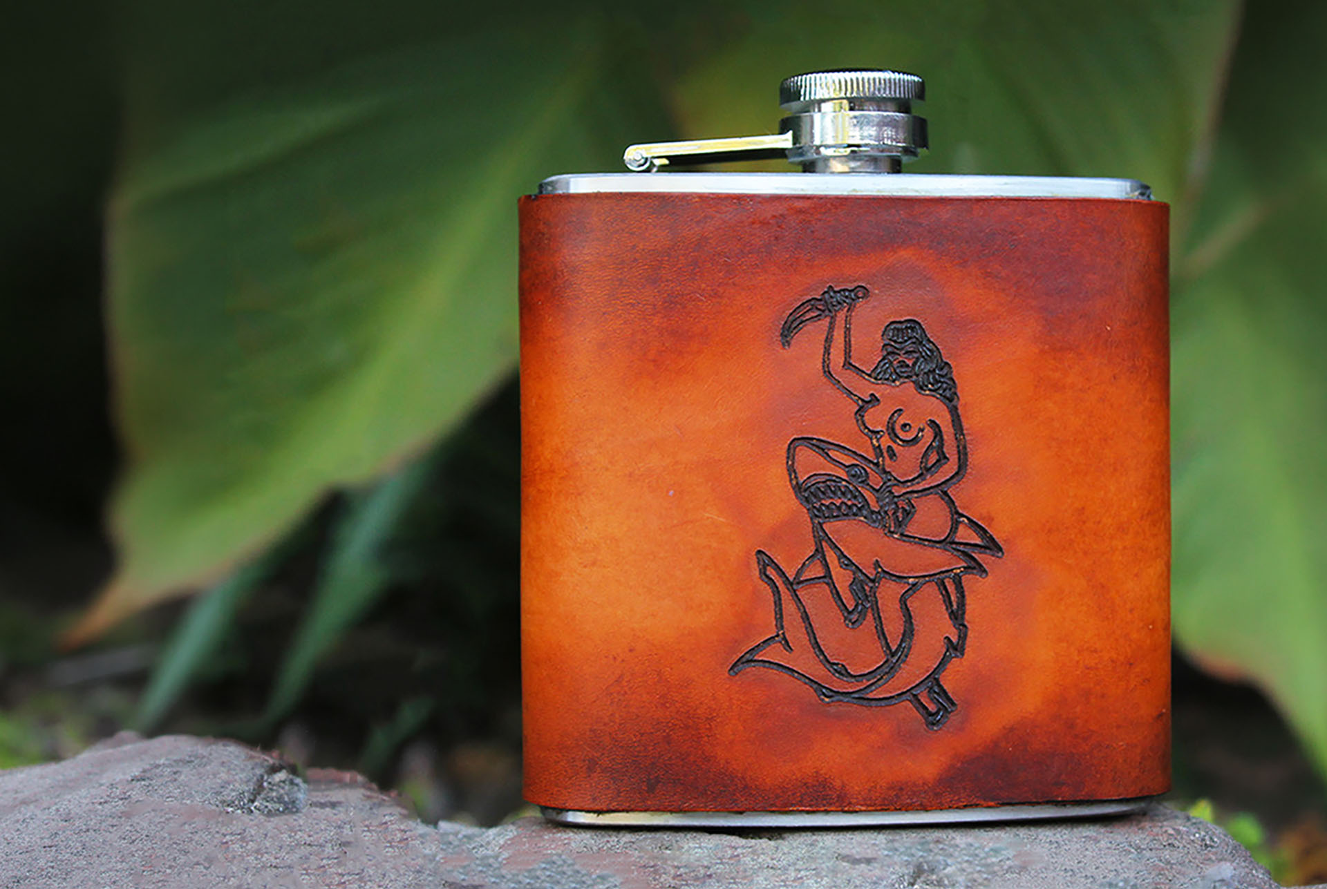 The finished J. James leather wrapped flask with the original design drawings behind it
