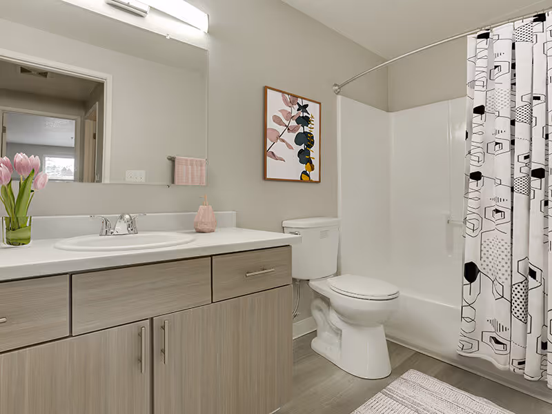 Bathroom with light wood cabinets and shower tub combo virtually staged