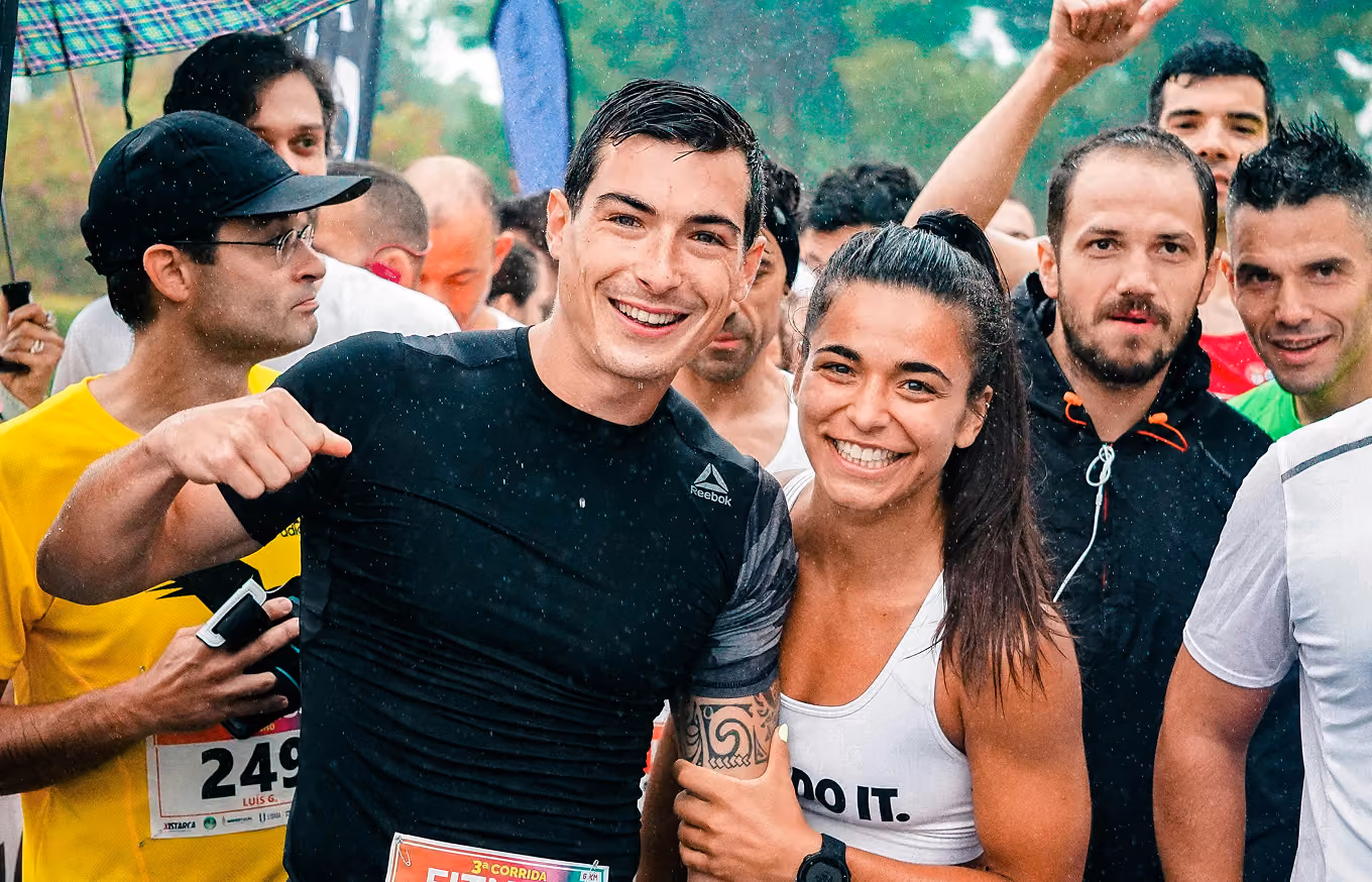 Smiling runners posing together at a fitness race event in light rain.