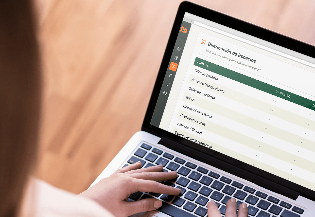 Person typing on a laptop showing a screen with a Spanish workspace distribution inventory table.