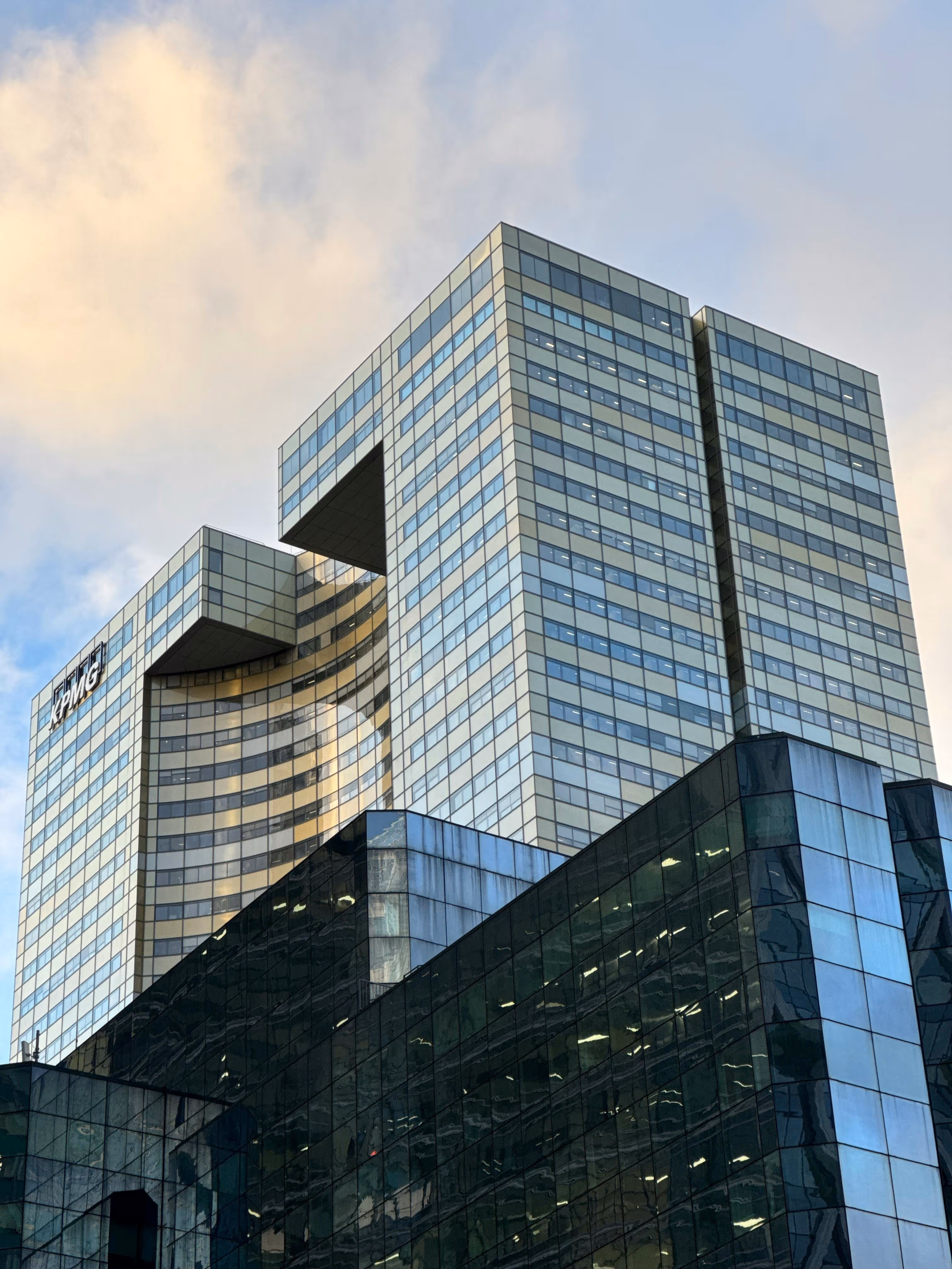 Hoog kantoorgebouw met glasgevels en het KPMG-logo, onder een bewolkte hemel.