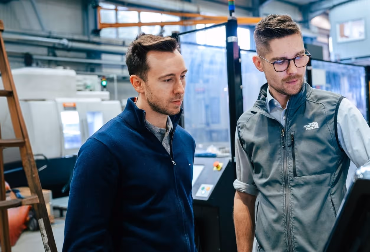 Zwei Männer betrachten eine Maschine in einer modernen Fabrikumgebung.