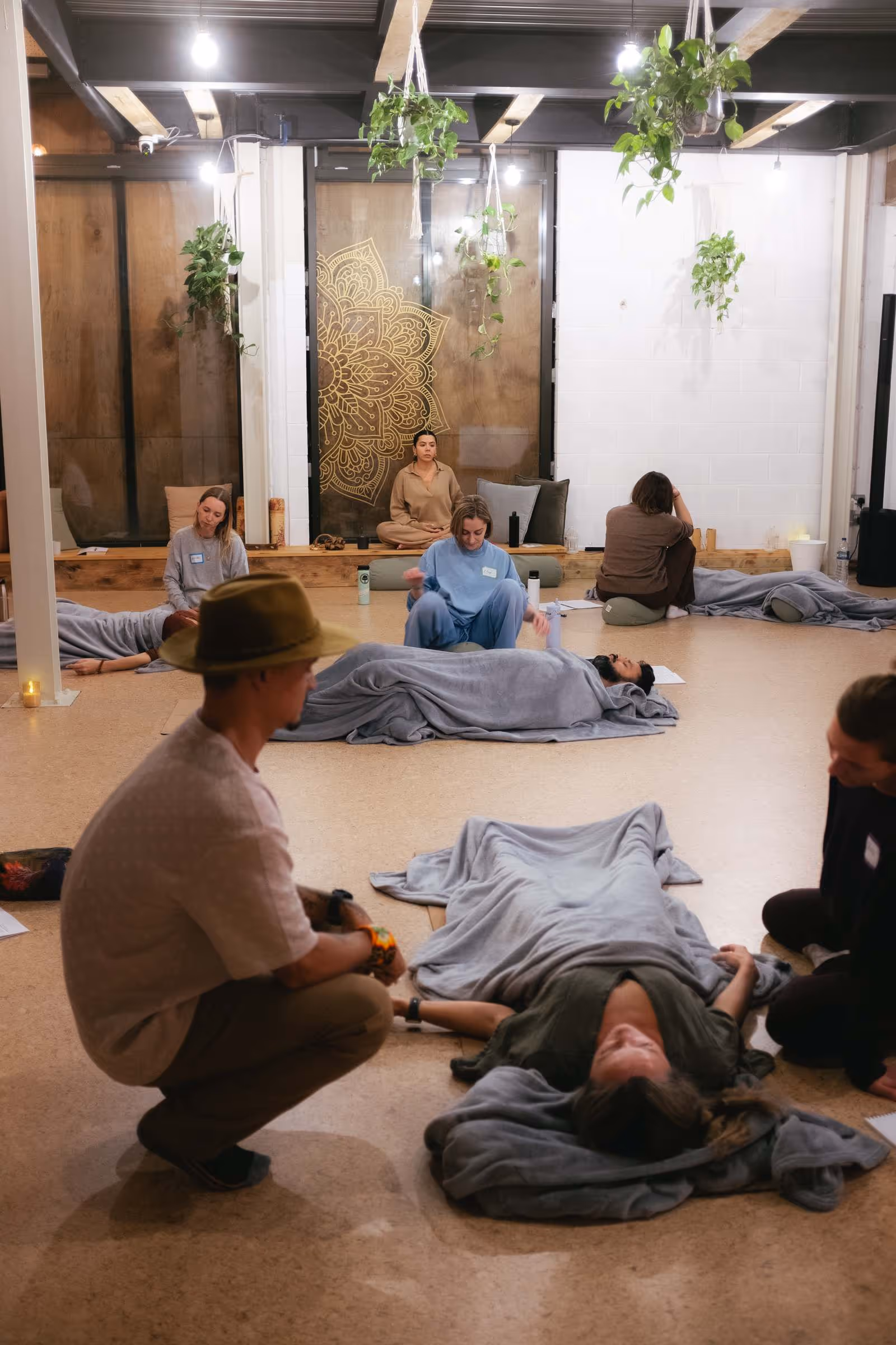 Group of people in a calm room, some lying covered with blankets on the floor during a breathwork session.