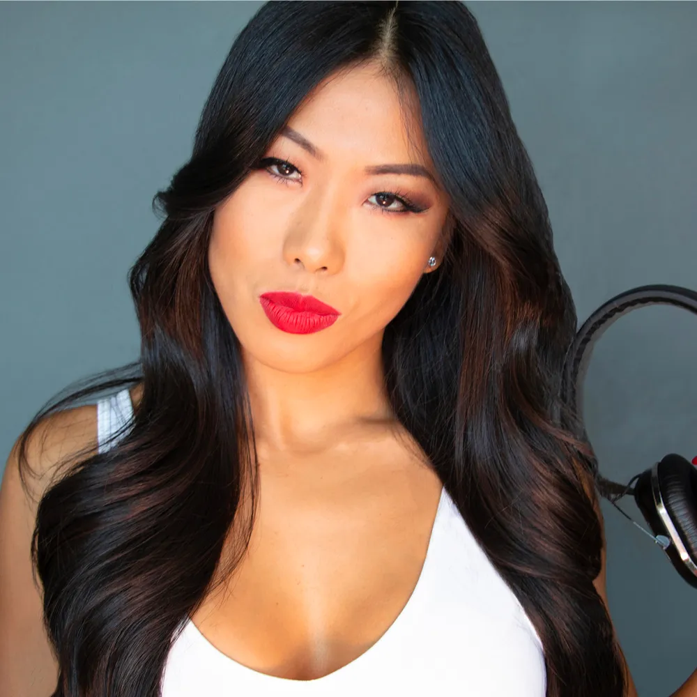 Portrait of Chika in a white top with headphones in the background.