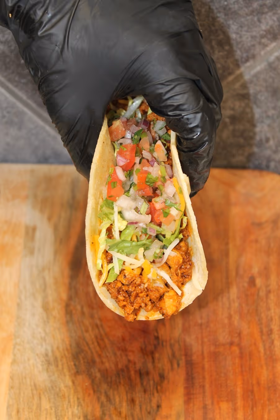 A person is holding a taco with meat and vegetables.