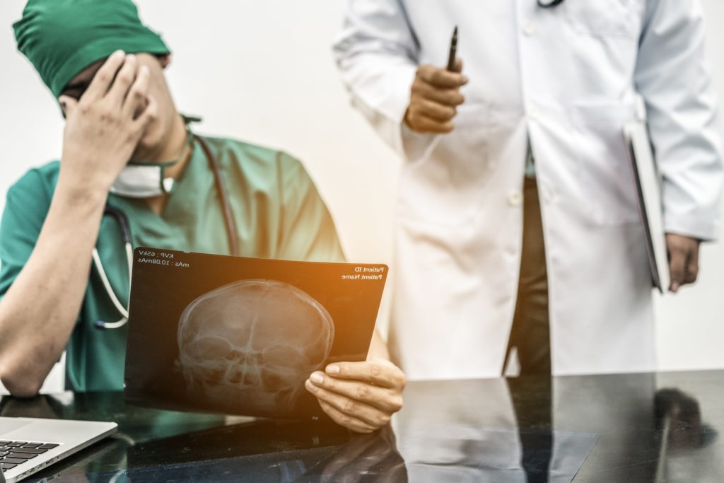 Surgeon looking at x-ray image with their face in their palm