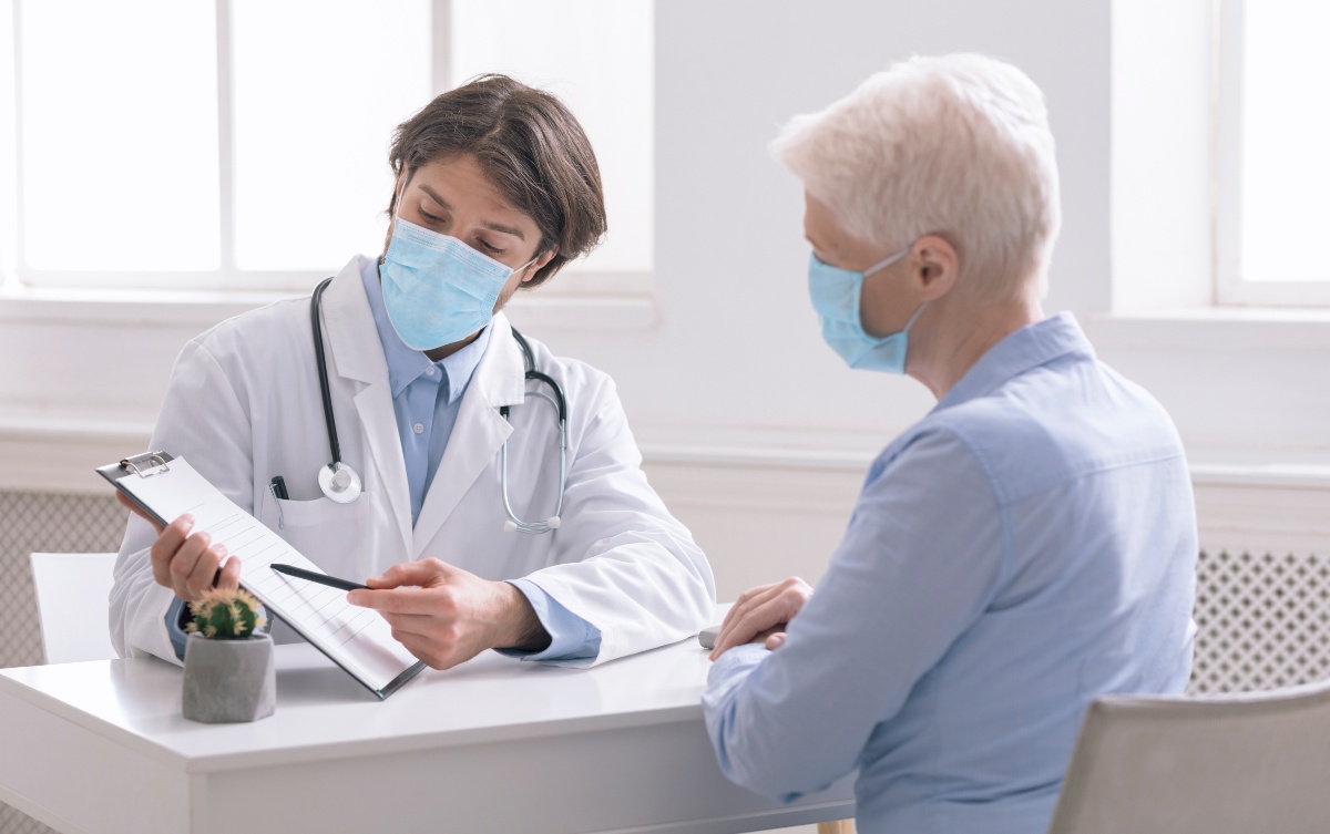 Doctor sitting at desk with elderly woman explaining medical results to her