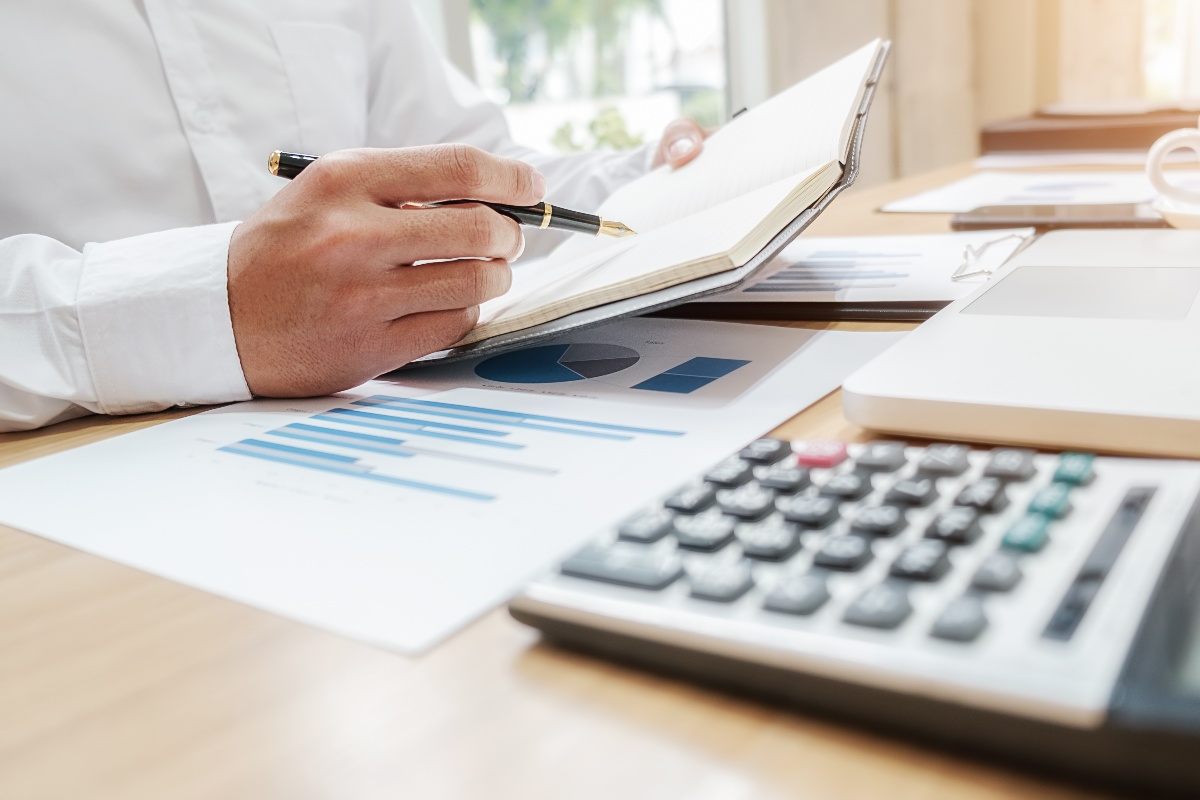 Doctor sitting at desk with notepad and calculator calculating figures