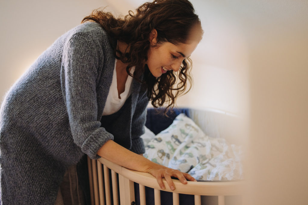 Mother peeking into a bassinet looking at baby