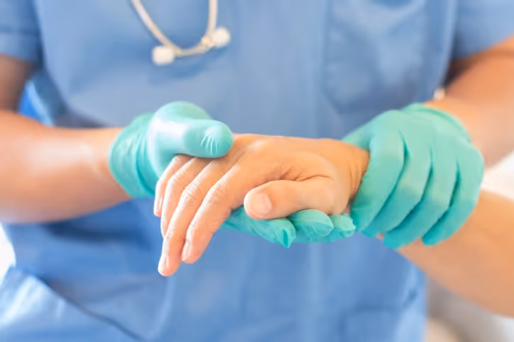 A surgeon with gloved hands holds the hand of a patient receiving anesthesia. Anesthesiologists can be guilty of doctor sexual assault.