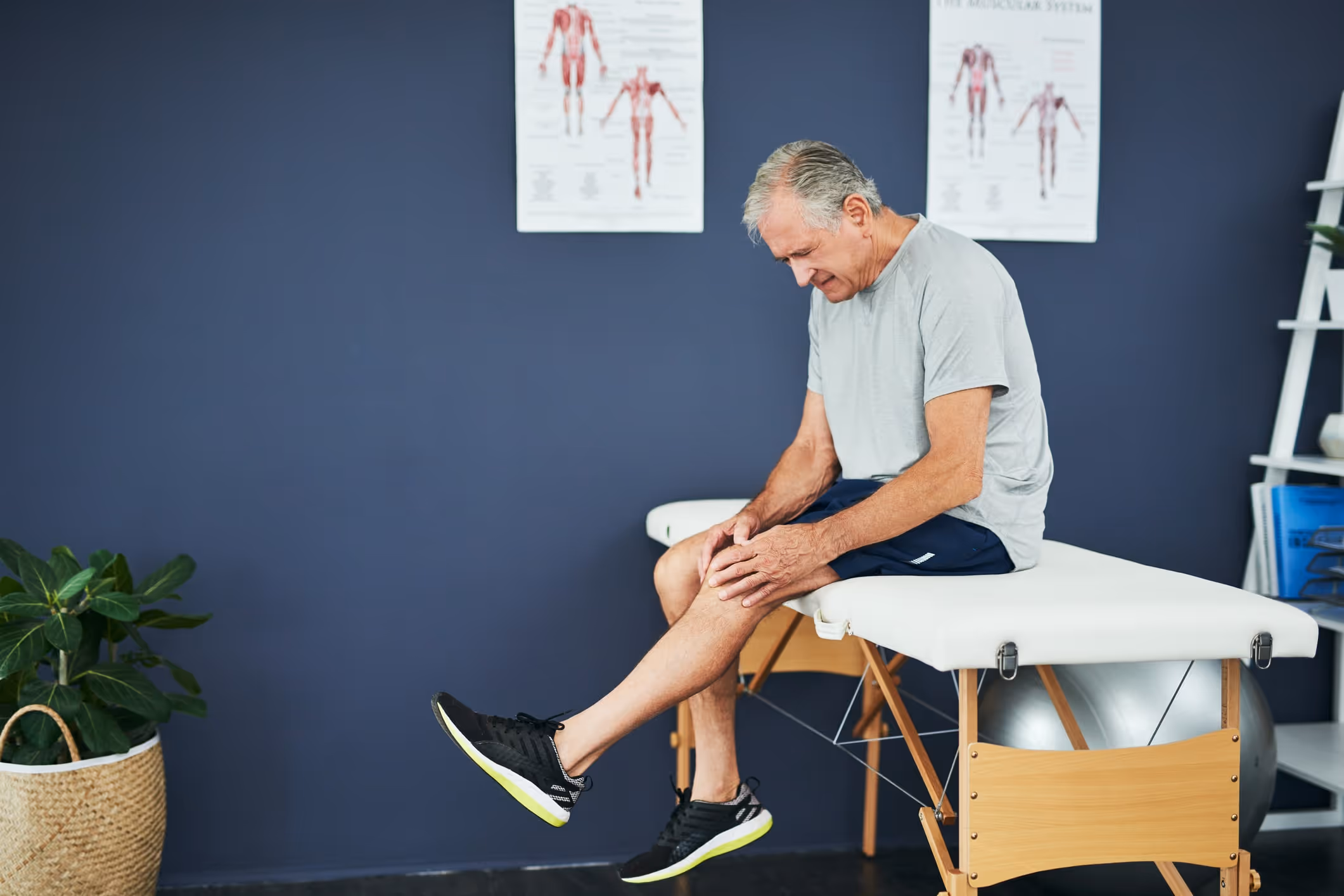 Elderly man in phyiscal therapy rehab room holding knee in pain|Burnt power cord that has caught fire plugged into a singed power outlet