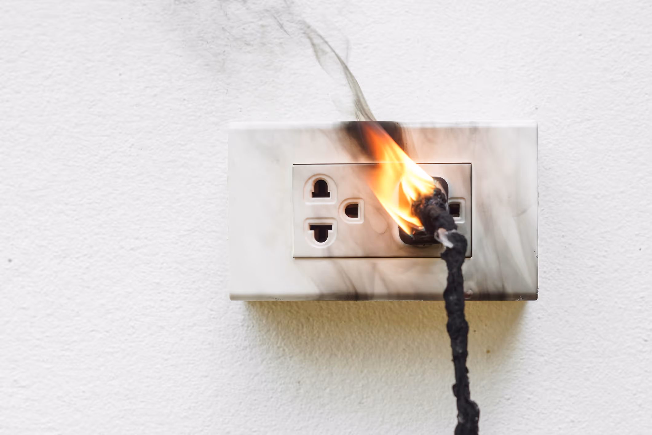 Burnt power cord that has caught fire plugged into a singed power outlet