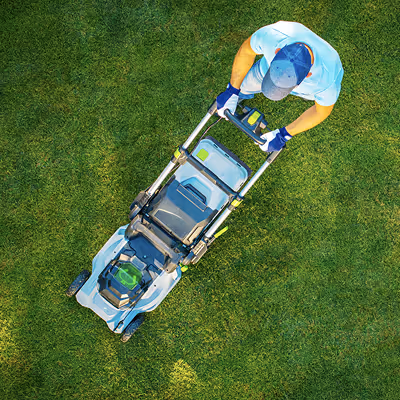 Person mowing green grass with a white and green lawn mower, viewed from above.