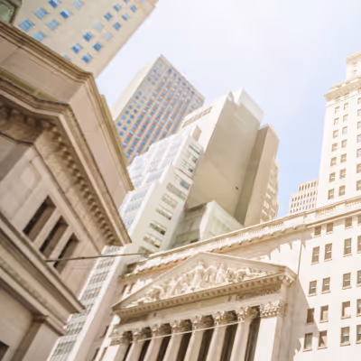 Low angle of tall buildings and classical architecture against a bright sky.